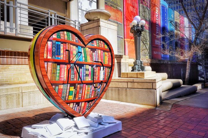 Large heart sculpture with "KC" embossed and painted to look like library shelves full of books.