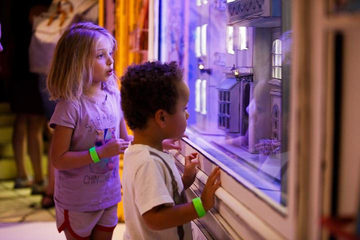 Two small children staring in wonder at a miniature house display