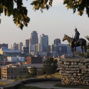 Statue of man on a horse, with the Kansas City skyline in the background